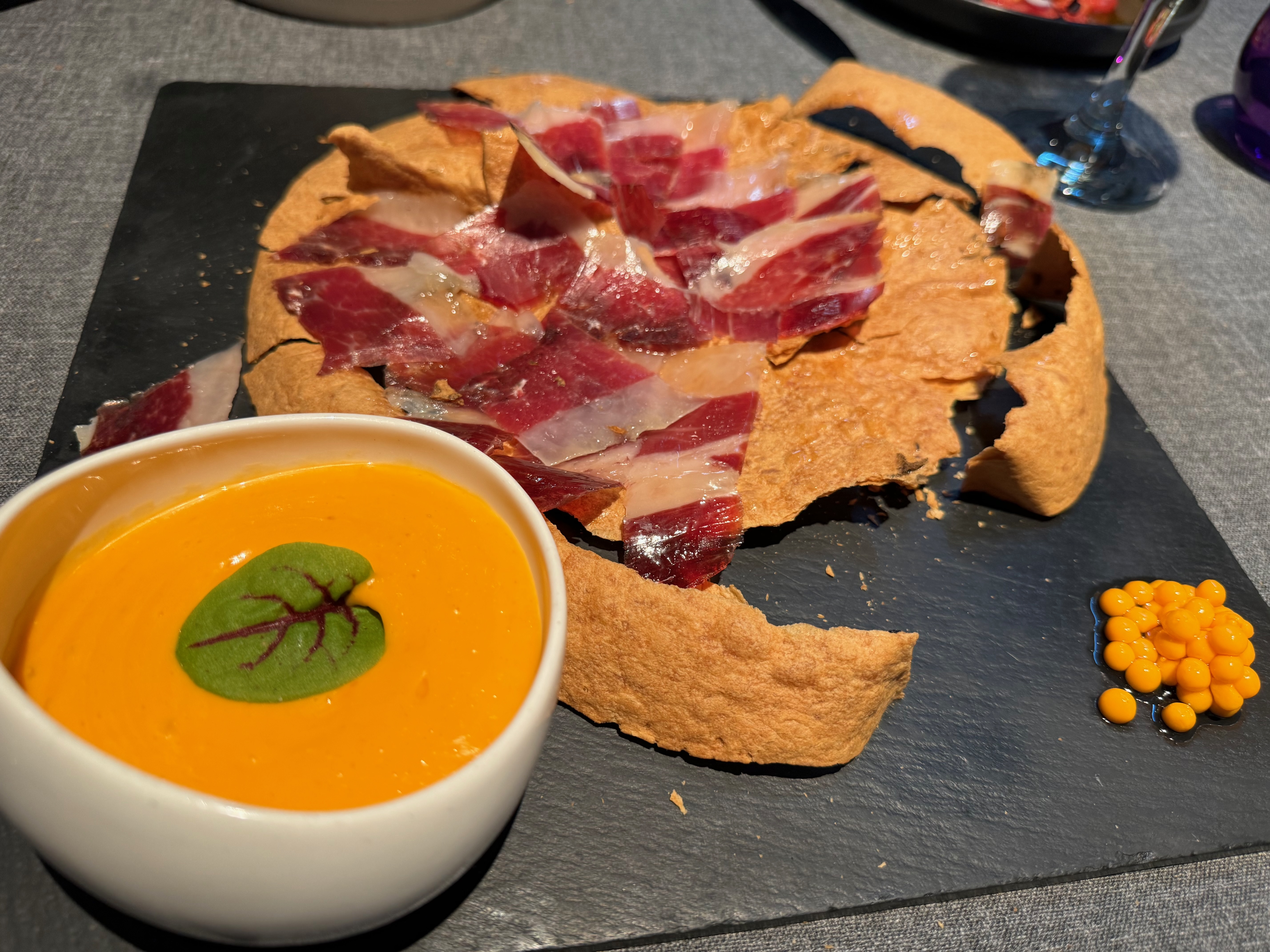 Sliced Bellota Jamón with salmorejo and regañá crushed with mallet.